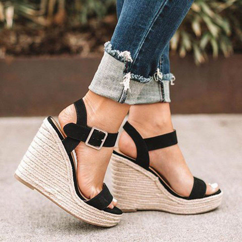 Sandales compensées noires en toile avec semelle en corde, portées avec un jean retroussé. Mode estivale, chaussures tendance pour femmes.