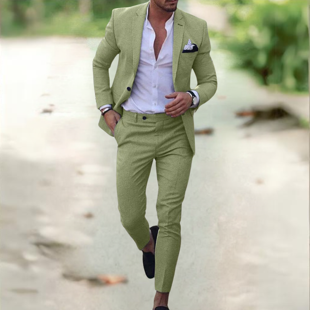 Homme élégant en costume vert clair, chemise blanche ouverte, marchant sur un chemin extérieur. Mode masculine, style décontracté chic.