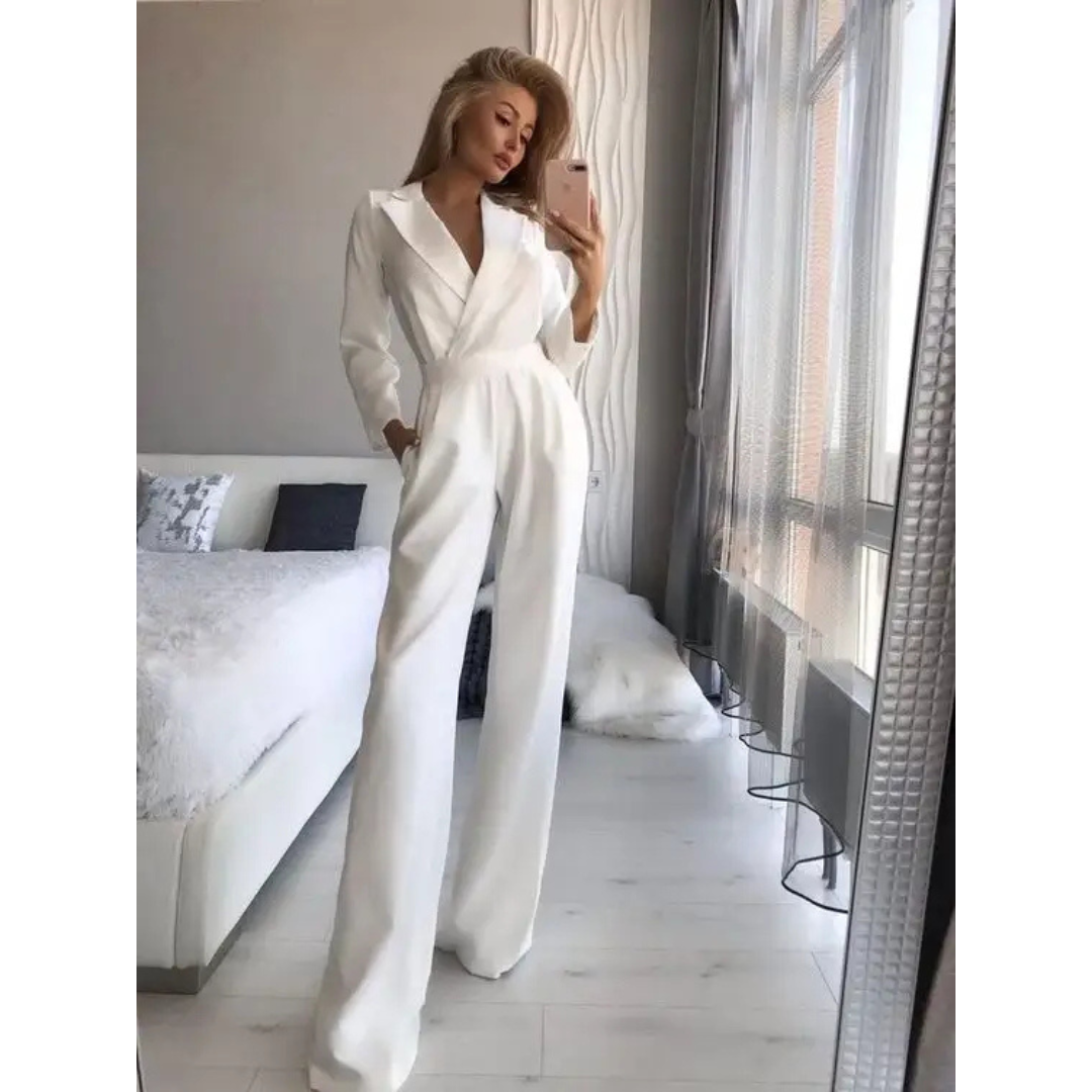 Femme en combinaison blanche élégante, posant devant un miroir dans une chambre moderne et lumineuse. Mode féminine, style chic, tenue tendance.