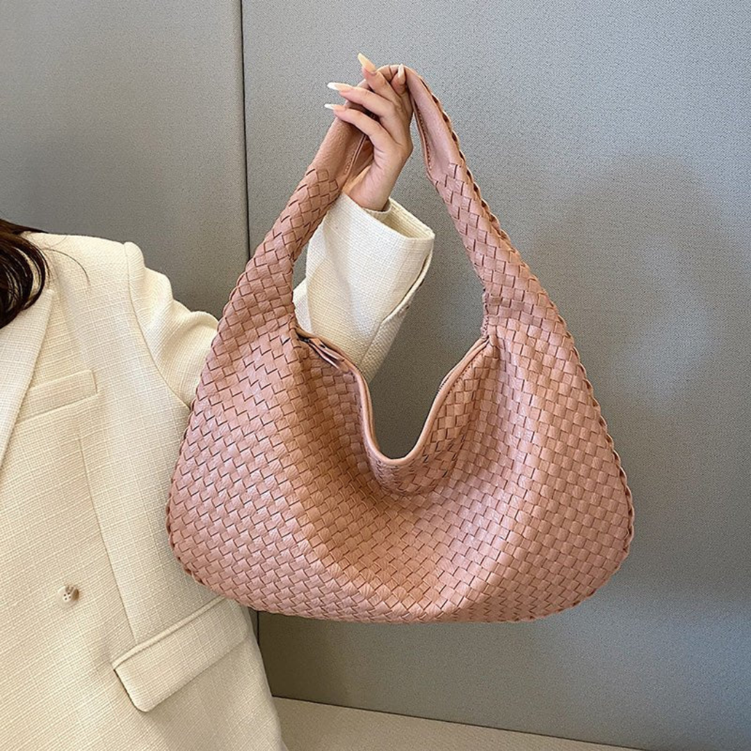 Sac à main tressé rose pâle, porté par une femme en veste blanche. Accessoire mode élégant, tendance, idéal pour un look chic et moderne.
