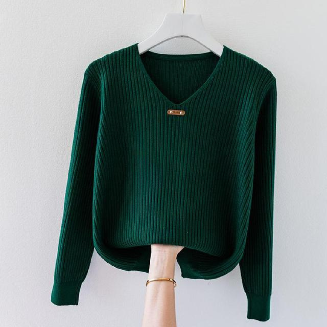 Pull vert en tricot côtelé avec col en V, suspendu sur un cintre blanc. Mode automne-hiver, vêtement chaud et élégant pour femme.