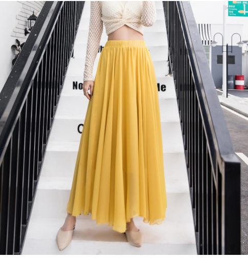 Jupe longue jaune fluide portée par une femme sur un escalier, mode élégante, tenue chic, style urbain, vêtements féminins tendance.