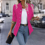 Femme en veste rose vif avec manches imprimé léopard, tenant un smartphone et un sac noir, marchant en ville. Mode urbaine, style chic.