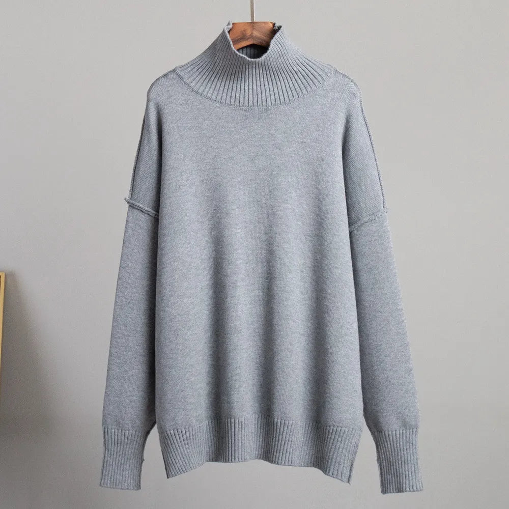 Pull-over gris à col roulé en laine, suspendu sur un cintre en bois. Design minimaliste, manches longues, idéal pour l'hiver et la mode décontractée.