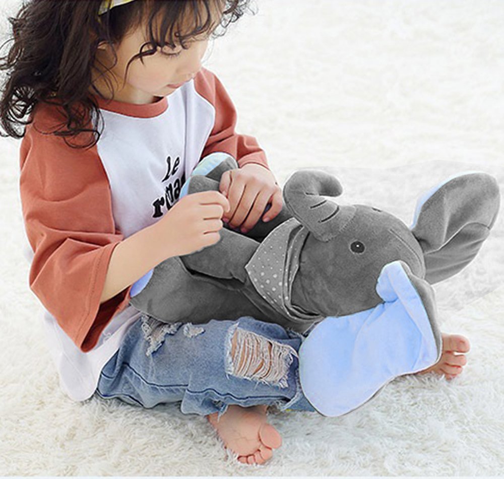Enfant jouant avec une peluche éléphant gris sur un tapis blanc, vêtue d'un t-shirt blanc et rouge et d'un jean déchiré. Jouet doux et câlin.
