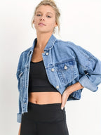 Femme portant une veste en jean bleu sur un top noir, posant avec assurance. Mode décontractée, tendance, style urbain, vêtements féminins.