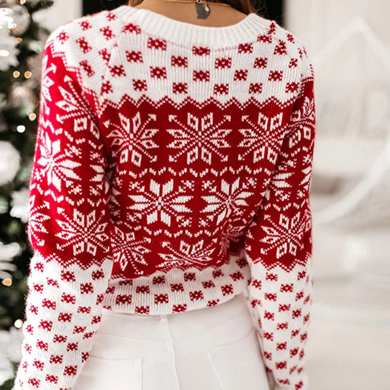 Pull de Noël rouge et blanc avec motifs flocons de neige, femme de dos, ambiance festive, mode hiver, près d'un sapin décoré.