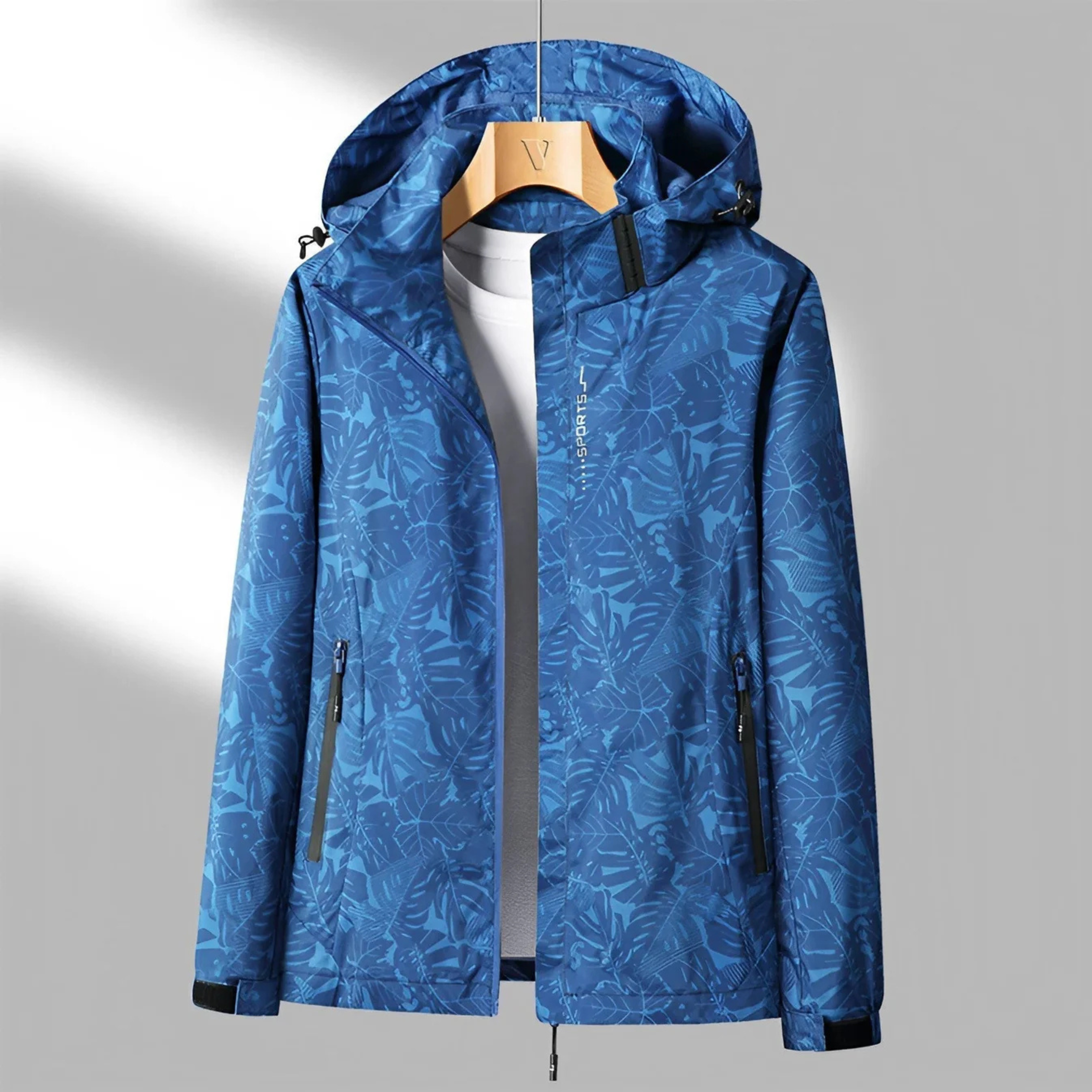 Veste imperméable bleue à motifs floraux, capuche ajustable, fermetures éclair noires, idéale pour randonnée et activités extérieures.