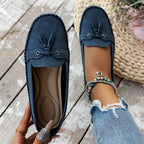 Mocassins bleus en daim pour femme avec lacets, portés avec un jean déchiré. Chaussures confortables et élégantes sur fond de bois clair.