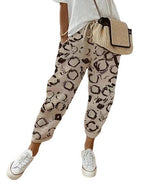 Pantalon ample beige à motifs noirs, porté avec un t-shirt blanc et des baskets blanches, sac à bandoulière en paille. Mode décontractée femme.