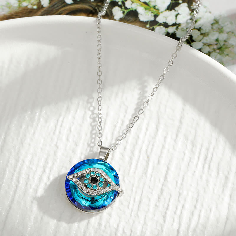 Collier pendentif œil bleu en cristal sur assiette blanche, bijou tendance, protection contre le mauvais œil, mode féminine élégante.