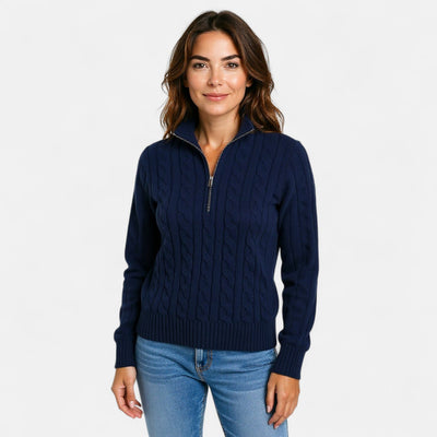 Femme portant un pull bleu marine à col zippé, motif torsadé, manches longues, sur fond blanc. Mode automne-hiver, style décontracté et élégant.