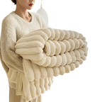 Femme tenant une couverture en fausse fourrure beige, douce et moelleuse, idéale pour le confort et la décoration intérieure moderne.