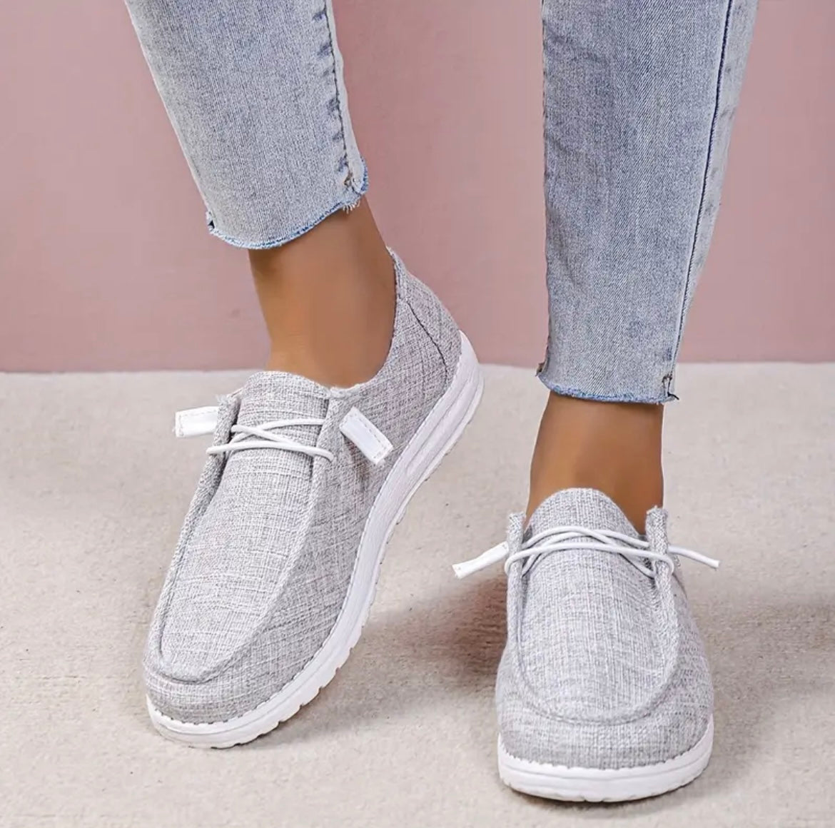 Chaussures décontractées grises pour femmes, style mocassin, avec lacets blancs, portées avec un jean clair. Mode féminine, confort, tendance.