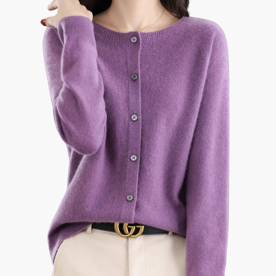 Femme portant un cardigan en cachemire violet avec boutons, ceinture noire avec boucle dorée, sur fond blanc. Mode élégante et confortable.