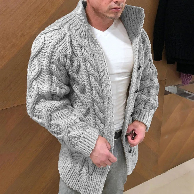 Homme portant un cardigan en tricot torsadé gris, col montant, sur un t-shirt blanc. Mode masculine, style hiver, vêtement chaud et élégant.