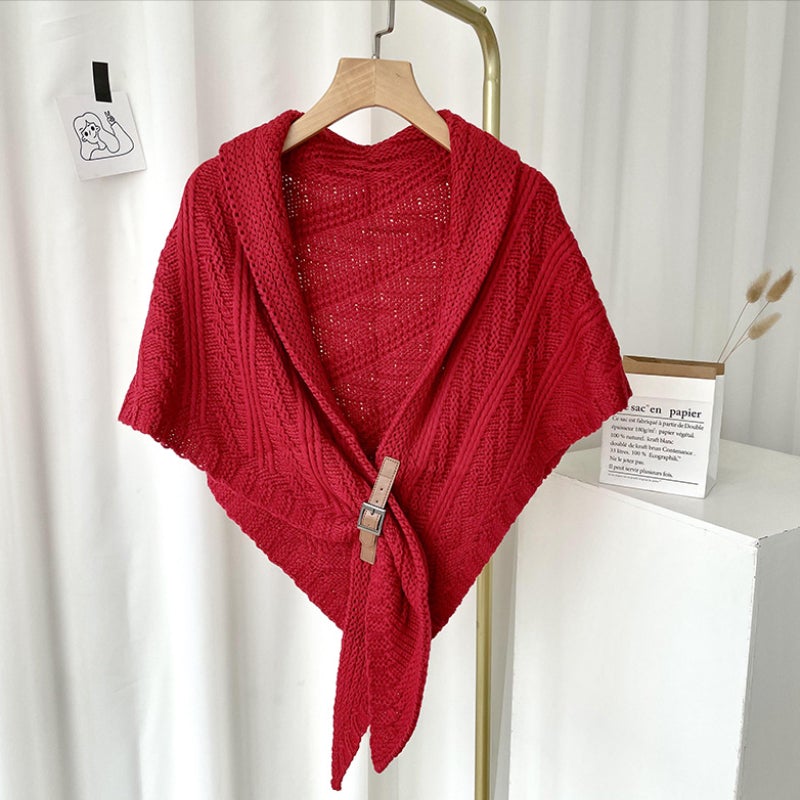 Châle rouge en tricot avec boucle en bois, suspendu sur cintre. Accessoire mode élégant, idéal pour l'hiver. Décoration intérieure minimaliste.