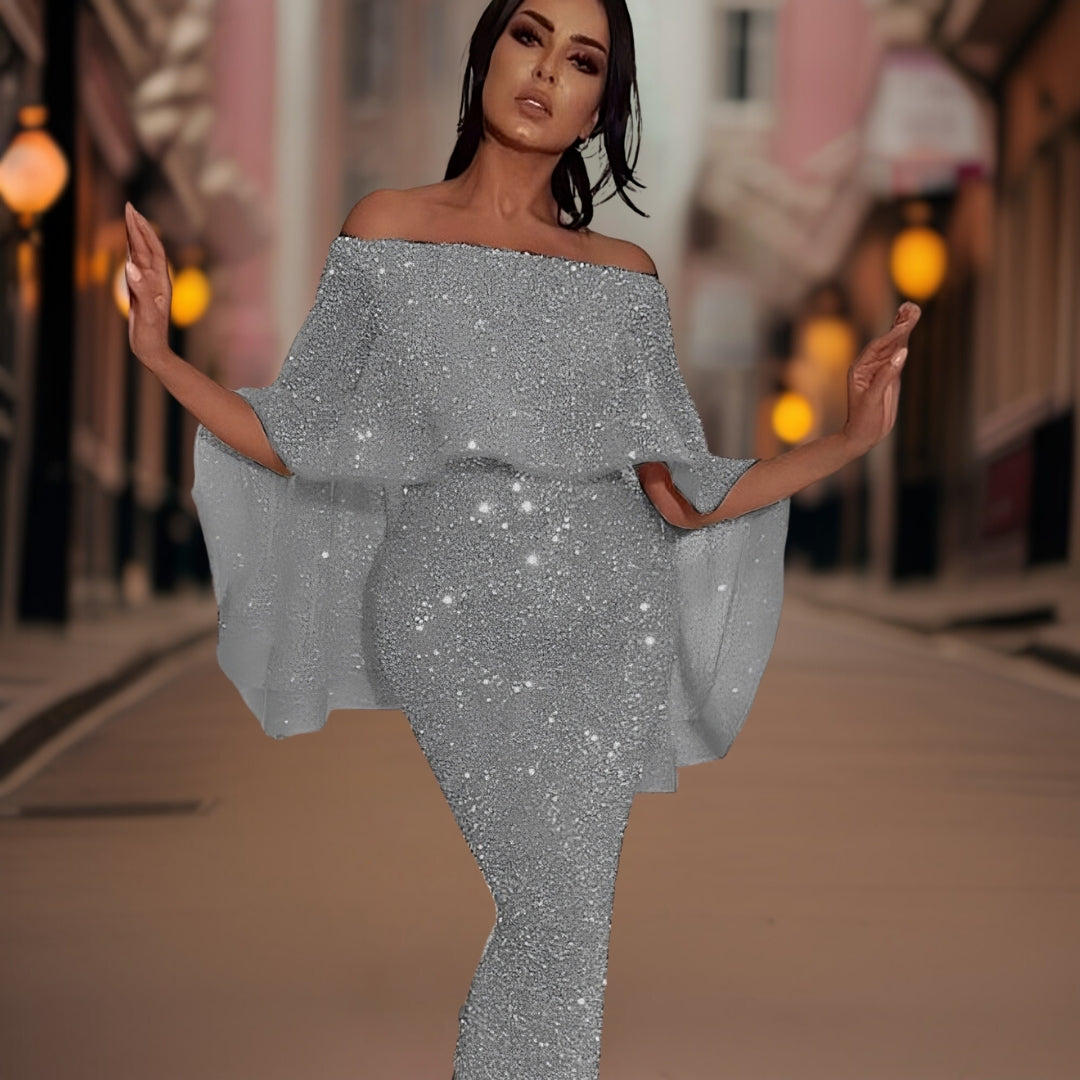 Robe de soirée scintillante argentée portée par une femme élégante dans une rue urbaine, éclairée par des lampadaires, style glamour et chic.