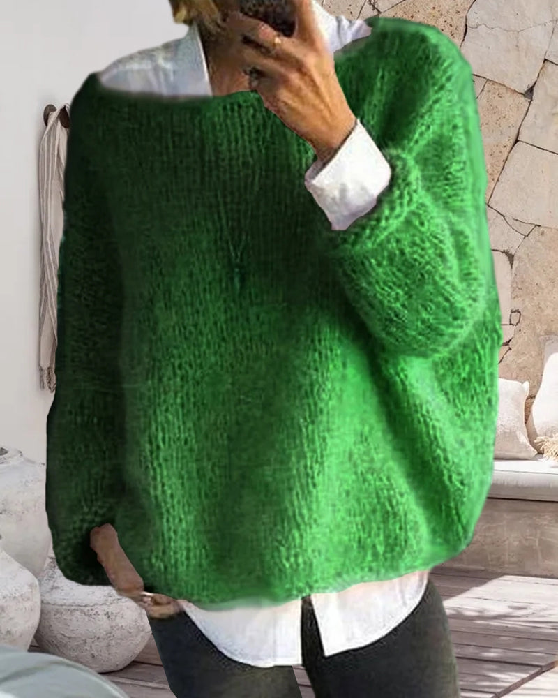 Personne portant un pull vert en laine épaisse, sur une chemise blanche, dans un intérieur moderne. Mode automne-hiver, style décontracté.