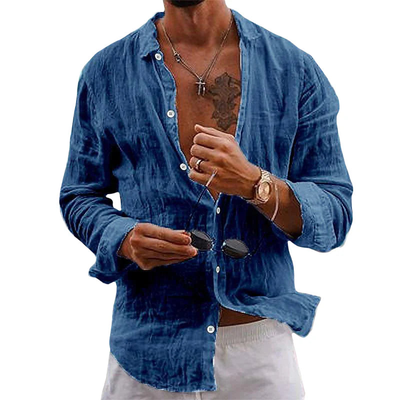 Homme portant une chemise en lin bleu décontractée, ouverte, avec col en V, tenant des lunettes de soleil. Style estival, mode masculine tendance.
