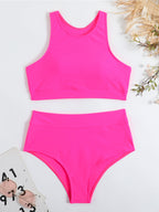 Maillot de bain deux pièces rose vif pour femme, style sportif, sur fond blanc avec lunettes de soleil et accessoires d'été.
