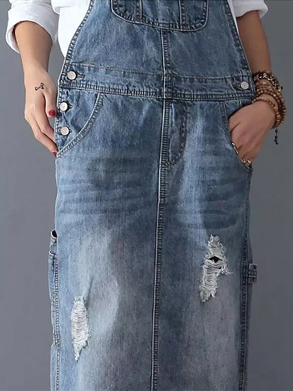 Robe salopette en jean délavé avec poches, boutons argentés et détails déchirés. Mode décontractée, tendance denim, style urbain.