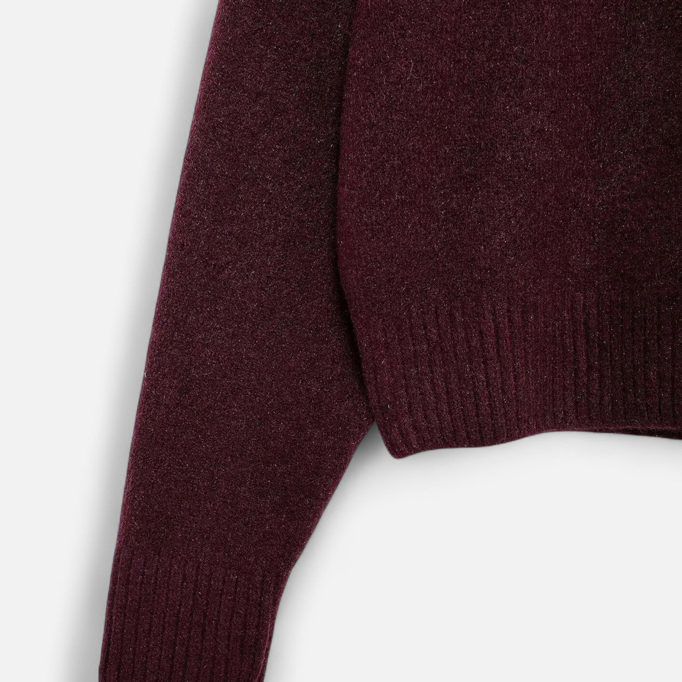 Manche de pull en laine bordeaux, texture douce et côtelée, mode automne-hiver, vêtement chaud et élégant pour homme ou femme.