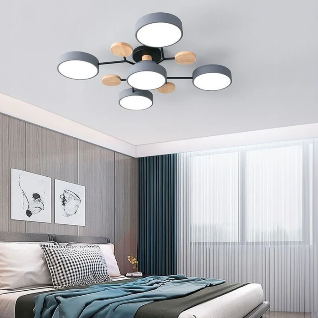 Plafonnier moderne à LED avec abat-jours circulaires noirs et détails en bois, installé dans une chambre élégante avec lit et rideaux bleus.