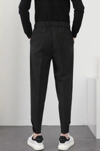 Homme en pantalon noir élégant, vue de dos, portant des baskets blanches. Mode masculine moderne, style décontracté chic.
