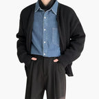 Homme portant un cardigan noir sur une chemise en jean et un pantalon noir. Mode masculine élégante, tenue décontractée chic, style automne-hiver.