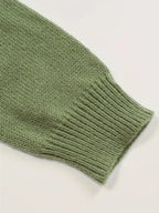 Manche de pull en laine verte, tricotée, texture douce et côtelée, mode automne-hiver, vêtement chaud et confortable, style décontracté.
