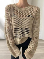 Pull en maille ajourée beige, manches longues, style décontracté, porté par une personne. Mode automne, tendance tricot, look moderne et élégant.