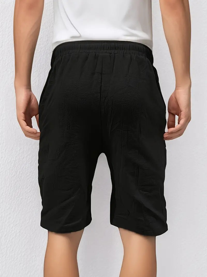 Homme en short noir, vue de dos, portant un t-shirt blanc. Mode décontractée, tenue estivale, style minimaliste.