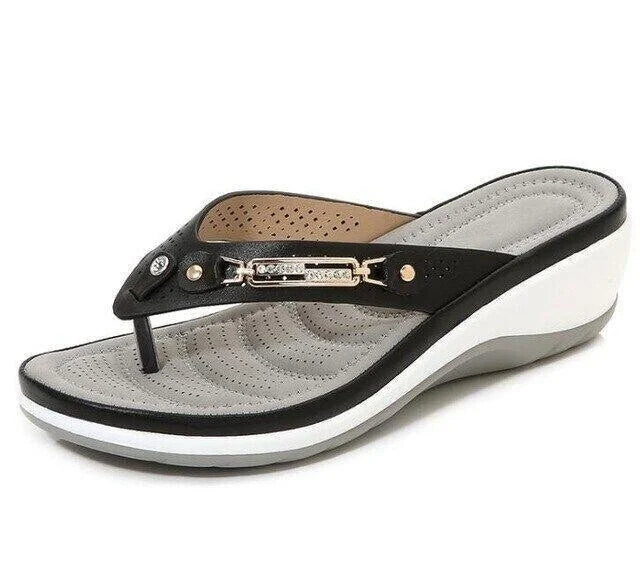 Sandale compensée noire et grise pour femme, avec semelle ergonomique et bride ornée de détails métalliques. Chaussure d'été confortable et élégante.