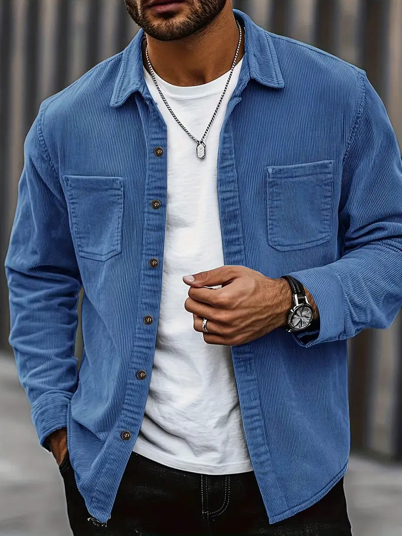 Homme portant une chemise en velours côtelé bleu, t-shirt blanc, montre-bracelet noire et collier argenté, mode masculine décontractée.