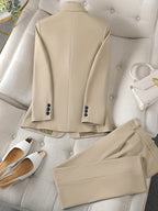 Costume beige élégant sur un canapé, accompagné de chaussures blanches à talons et d'un sac à main blanc. Mode chic, tenue formelle pour femmes.