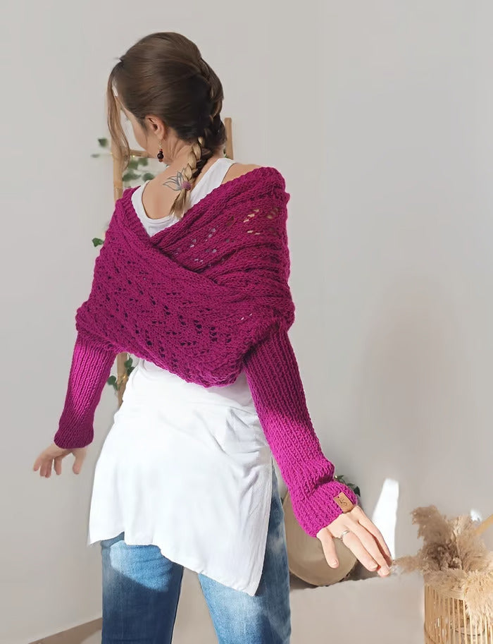 Femme portant un pull tricoté violet, dos tourné, cheveux tressés, sur fond de mur blanc avec plantes. Mode automne-hiver, style décontracté.
