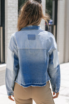 Femme portant une veste en jean délavé, vue de dos, devant un mur blanc. Mode urbaine, tendance denim, style décontracté.