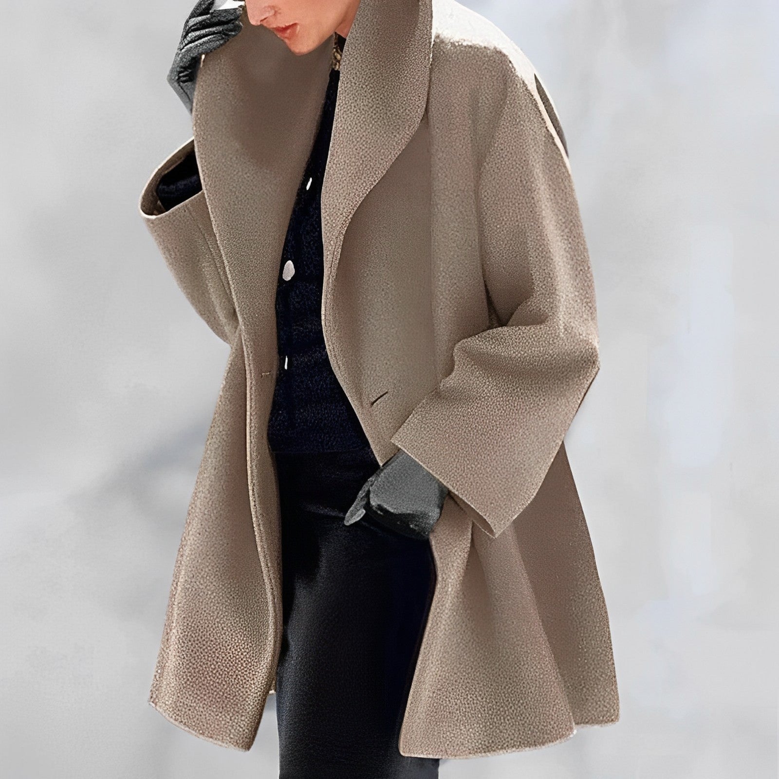 Manteau beige élégant pour femme, coupe ample, porté avec des gants noirs et un pull foncé. Mode automne-hiver, style chic et moderne.