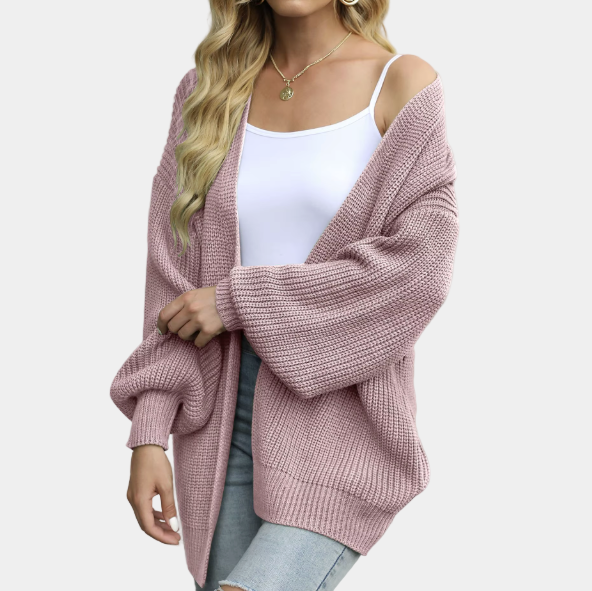 Femme portant un cardigan rose en maille, débardeur blanc et jeans déchirés. Mode automne, style décontracté, tendance féminine.