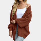Femme portant un cardigan en maille marron, débardeur blanc et jeans déchirés. Mode automne, style décontracté, tendance vêtements femme.