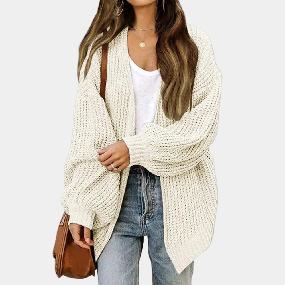 Femme portant un cardigan en tricot beige, t-shirt blanc, jean bleu et sac marron. Mode automne, style décontracté, tenue élégante.