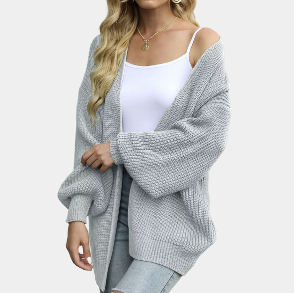 Femme portant un cardigan gris en maille, débardeur blanc et jeans déchirés. Mode automne, style décontracté, tenue confortable et élégante.