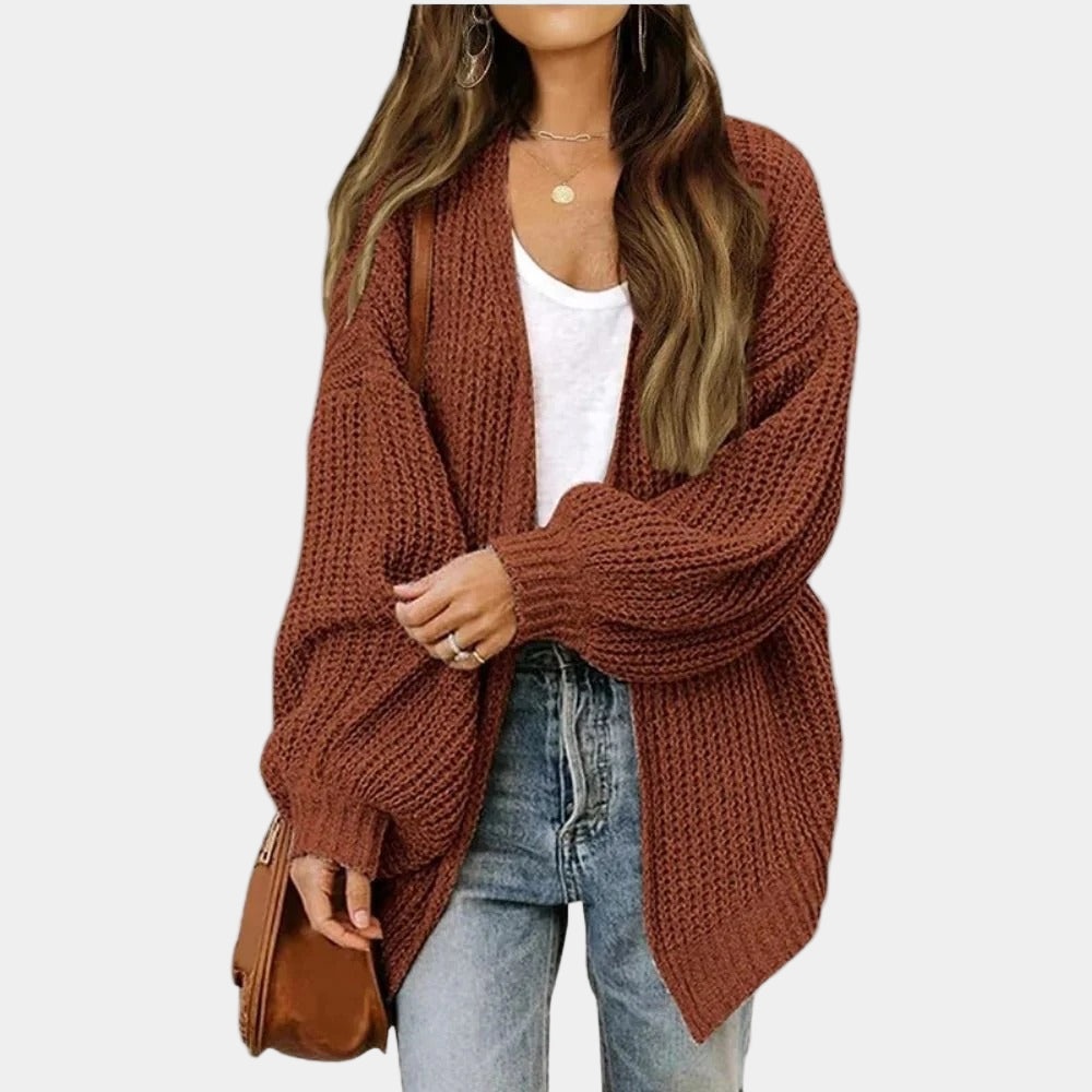 Femme portant un cardigan en maille marron, t-shirt blanc, jean bleu et sac à main marron. Mode automne, style décontracté, tendance féminine.