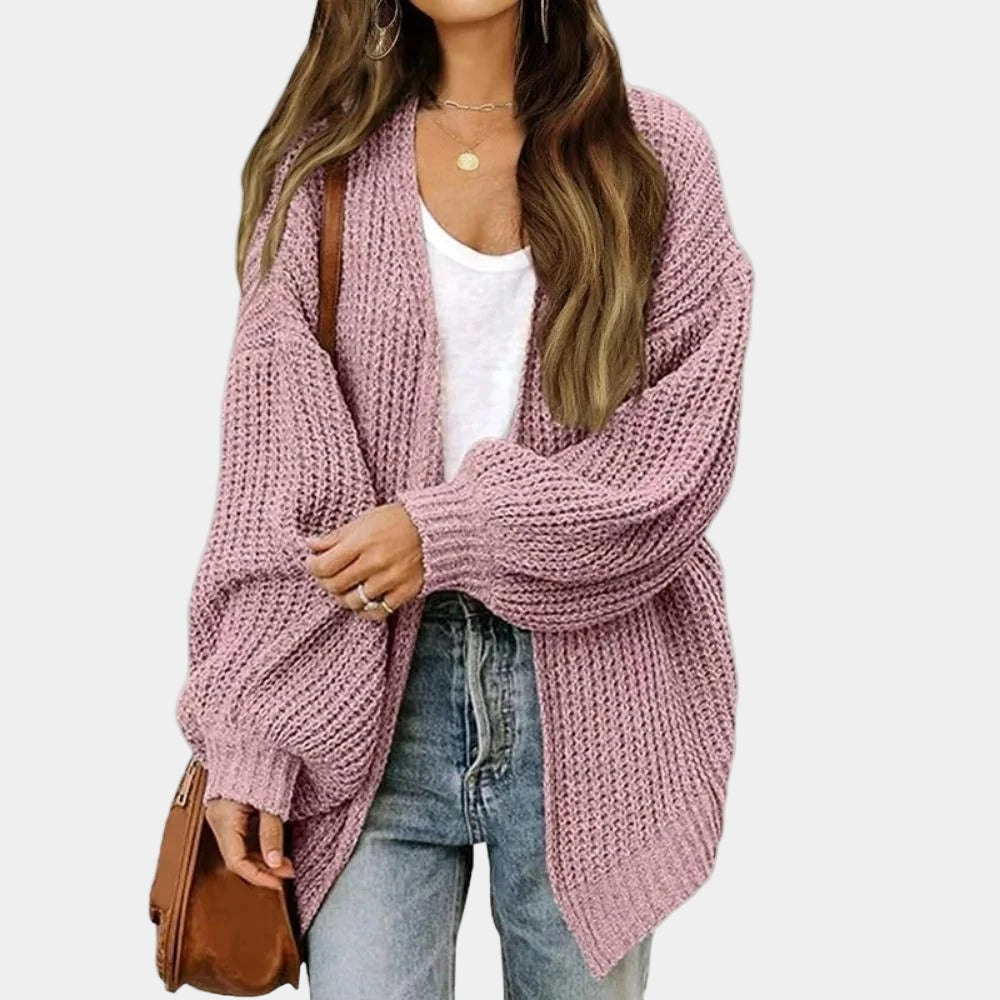 Femme portant un cardigan en maille rose, t-shirt blanc, jean décontracté et sac marron. Mode automne, style décontracté chic.