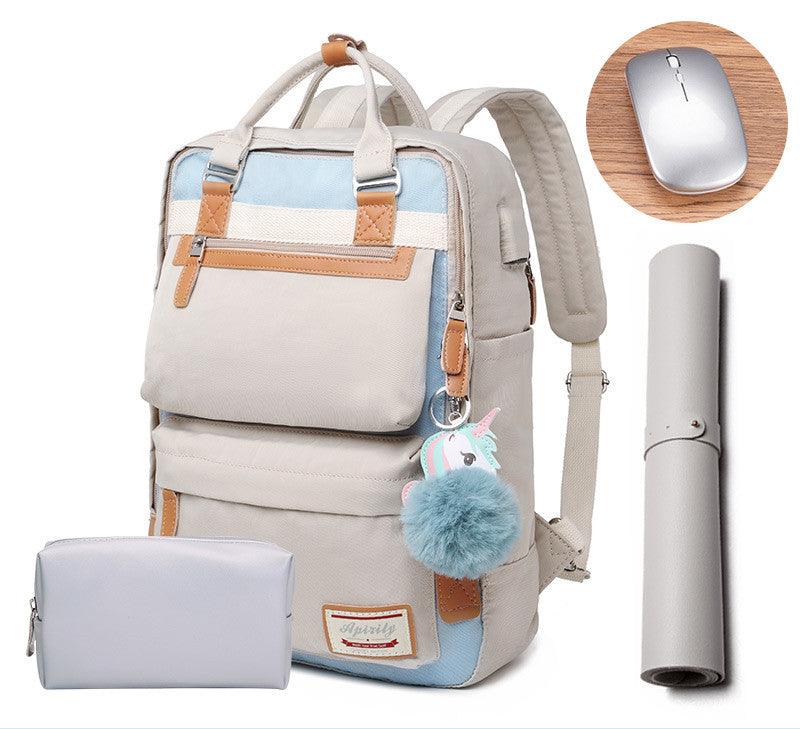 Sac à dos beige avec pompon bleu, pochette assortie, tapis de souris gris et souris sans fil argentée. Accessoires de bureau modernes et élégants.