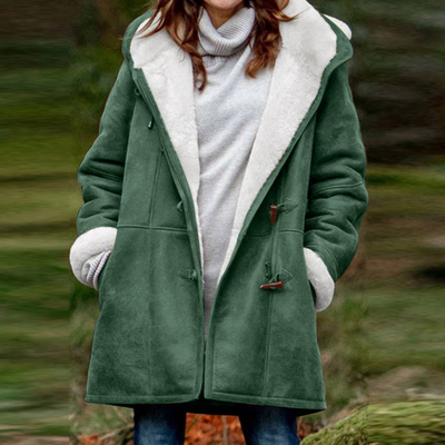 Femme portant un manteau vert en laine doublé de fourrure blanche, style hivernal, mode féminine, confort et chaleur, extérieur flou.