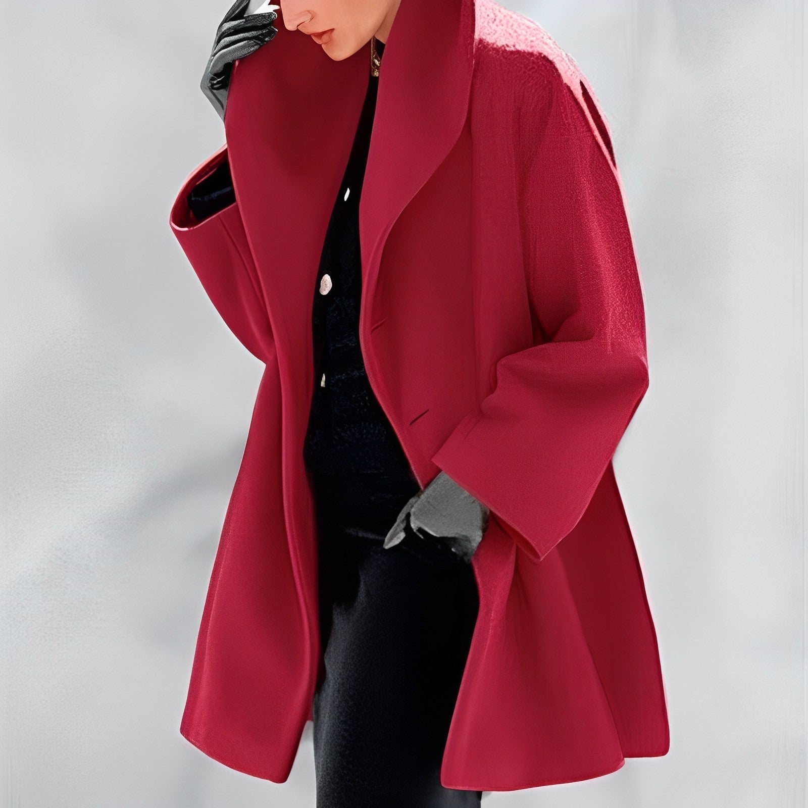 Femme portant un manteau rouge élégant, avec des gants noirs, sur fond neutre. Mode automne-hiver, style chic et moderne.