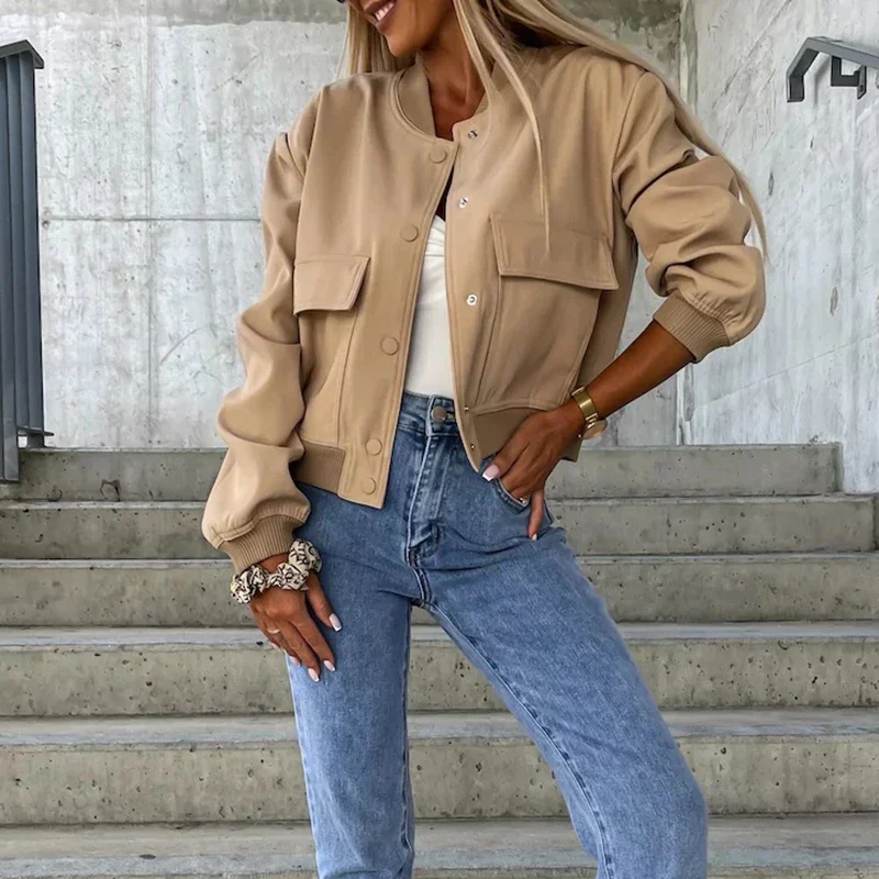 Femme portant une veste beige tendance et un jean bleu, posant sur des escaliers en béton. Mode automne, style décontracté, look urbain chic.