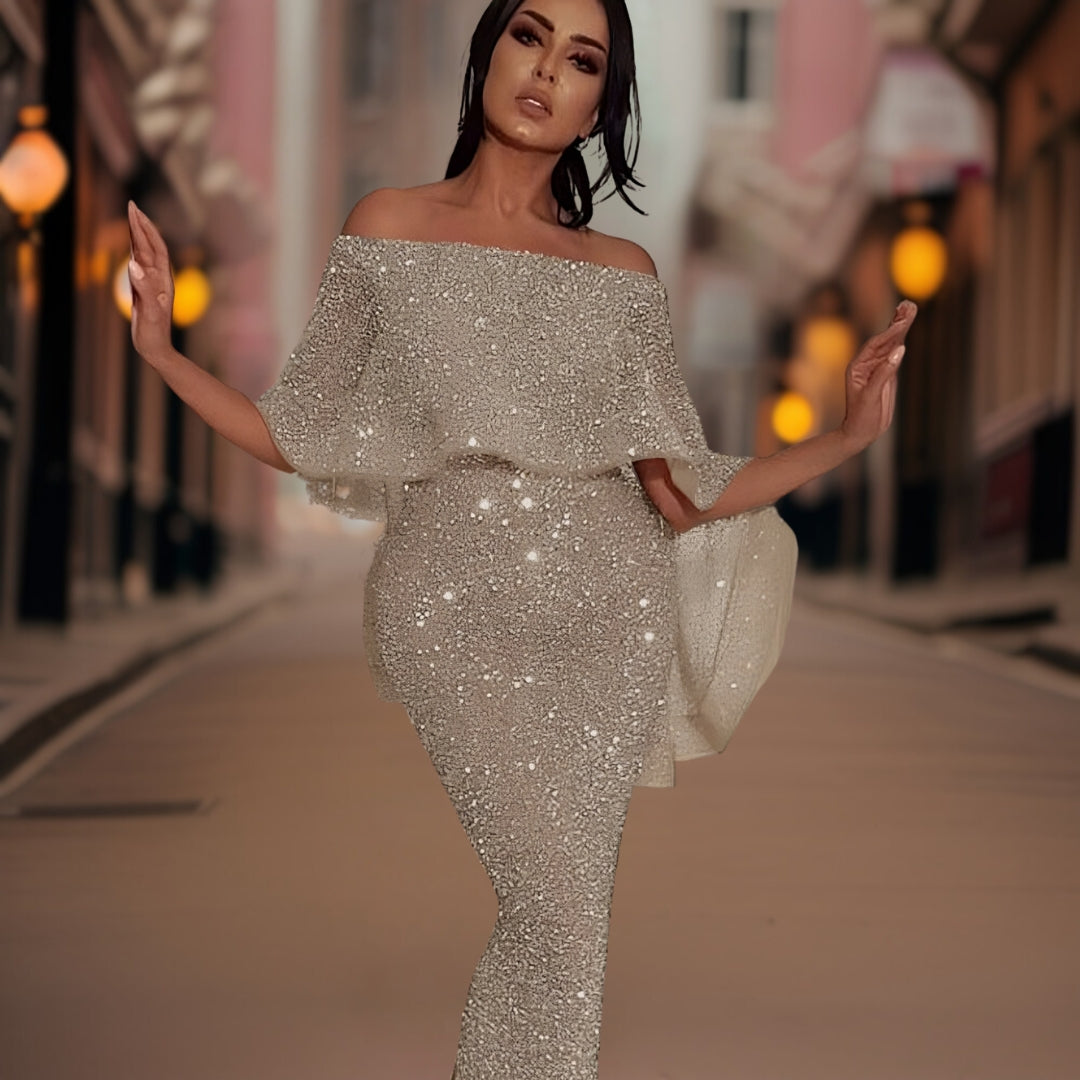 Robe de soirée scintillante argentée portée par une femme élégante dans une rue urbaine éclairée, mode glamour, tenue de fête chic.